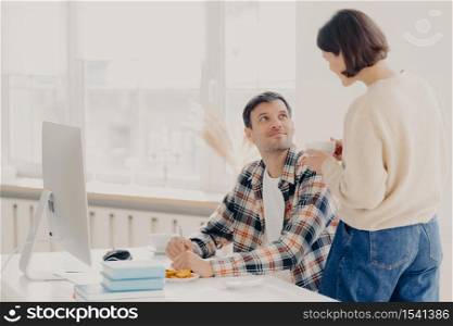 Family, paper work and technology concept. Husband and wife study contract agreement, read terms and conditions, discuss domestic bills, drinks coffee, man poses at desktop with modern computer