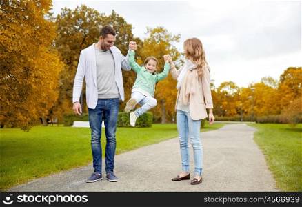 family, parenthood, adoption and people concept - happy mother, father and little girl walking in autumn city park and having fun