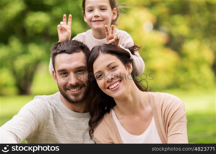family, parenthood, adoption and people concept - happy mother, father and little girl in summer park and having fun