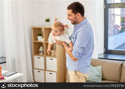 family, parenthood and fatherhood concept - happy father playing with little baby daughter at home. happy father playing with baby daughter at home