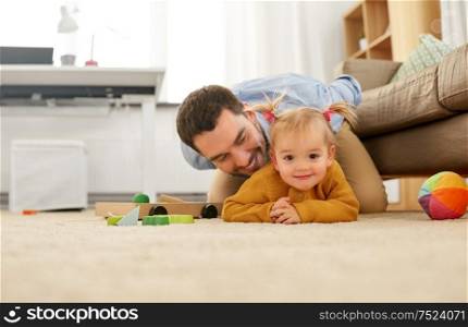 family, parenthood and fatherhood concept - happy father with little baby daughter playing on floor at home. happy father with baby daughter playing at home
