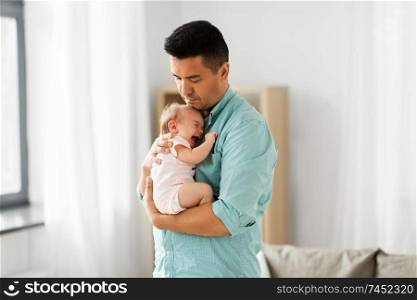 family, parenthood and fatherhood concept - middle aged father comforting little baby daughter at home. middle aged father with baby daughter at home