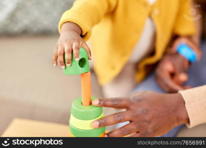 family, parenthood and people concept - close up of african american father and baby daughter playing with toy blocks at home. close up of baby playing toy blocks at home