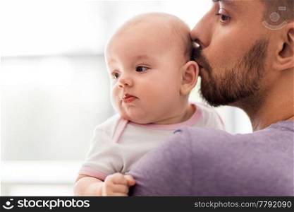 family, parenthood and people concept - close up of father kissing little baby daughter. close up of father kissing little baby daughter