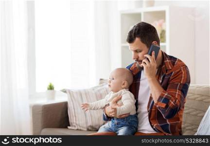 family, parenthood and people concept - father with little baby boy calling on smartphone at home. father with baby calling on smartphone at home