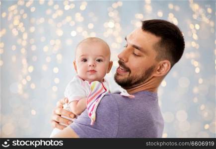 family, parenthood and people concept - father with little baby girl over festive lights background. father with little baby girl over festive lights