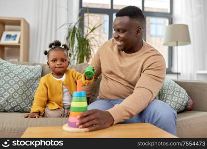 family, parenthood and people concept - happy african american father and baby daughter playing with toy blocks at home. african family playing with baby daughter at home