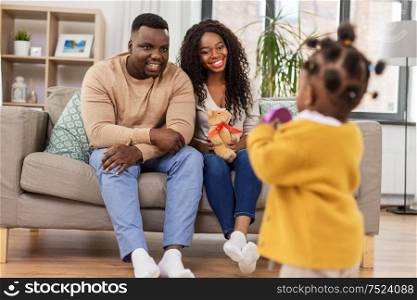 family, parenthood and people concept - happy african american mother and father looking at baby daughter at home. happy african family with baby daughter at home