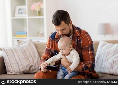 family, parenthood and people concept - happy father and little baby boy with smartphone boy at home. father and baby boy with smartphone at home