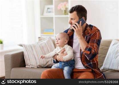 family, parenthood and people concept - happy father with little baby boy calling on smartphone at home. father with baby calling on smartphone at home