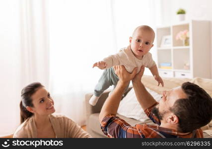 family, parenthood and people concept - happy mother and father playing with baby at home. happy mother and father playing with baby at home