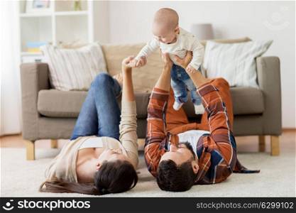 family, parenthood and people concept - happy mother and father playing with baby at home. happy family playing with baby at home