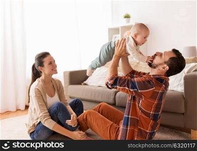 family, parenthood and people concept - happy mother and father playing with baby at home. happy mother and father playing with baby at home