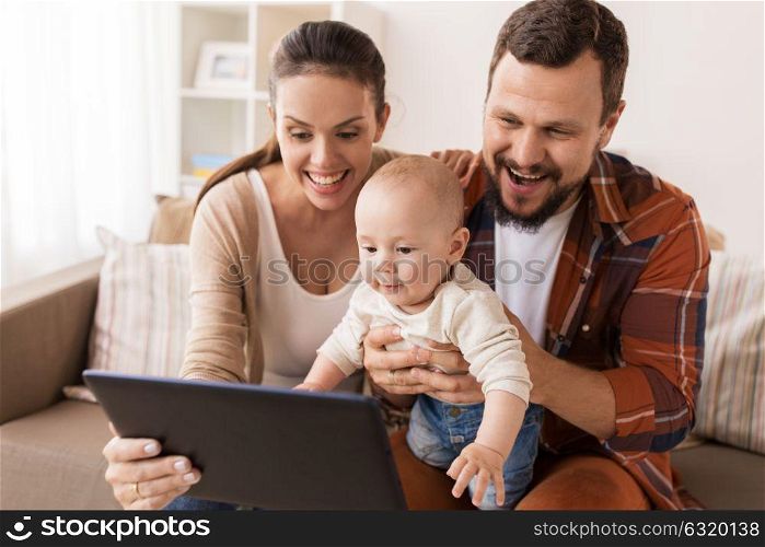 family, parenthood and people concept - happy mother and father showing tablet pc computer to baby at home. mother, father and baby with tablet pc at home