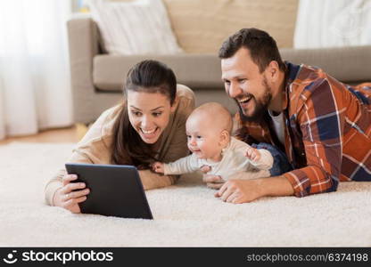 family, parenthood and people concept - happy mother and father showing tablet pc computer to baby at home. mother, father and baby with tablet pc at home