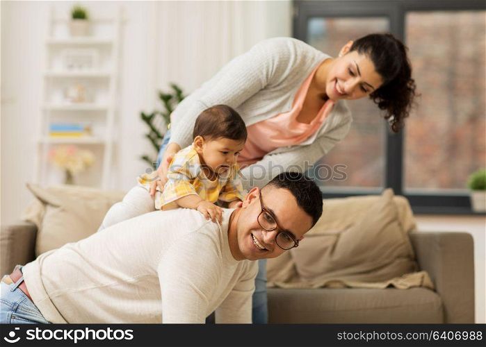 family, parenthood and people concept - happy mother, father and baby daughter playing at home. happy family and baby daughter playing at home