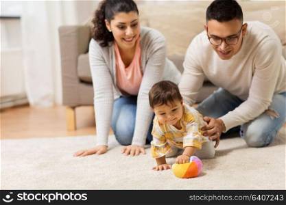 family, parenthood and people concept - happy mother, father and baby daugter playing with ball at home. happy family and baby daugter playing at home