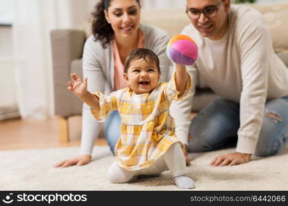 family, parenthood and people concept - happy mother, father and baby daugter playing with ball at home. happy family and baby daugter playing at home