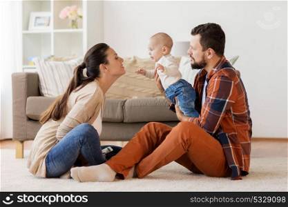 family, parenthood and people concept - happy mother, father with baby at home. happy family with baby having fun at home