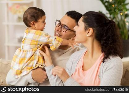family, parenthood and people concept - happy mother, father with baby daughter at home. happy family with baby daughter at home
