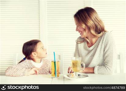 family, parenthood, communication and people concept - happy mother and little girl having dinner and talking at restaurant or cafe