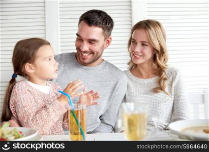 family, parenthood, communication and people concept - happy mother, father and little girl having dinner and talking at restaurant or cafe