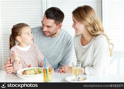 family, parenthood, communication and people concept - happy mother, father and little girl eating pasta for dinner and talking at restaurant or cafe
