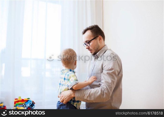family, parenthood, fatherhood, care and people concept - father taking care of little son at home