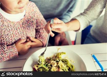 family, parenthood, food and people concept - close up of family eating pasta for dinner at restaurant or cafe