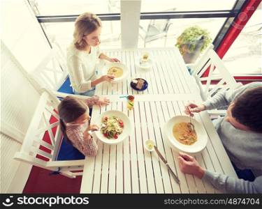 family, parenthood, food and people concept - happy mother, father and little girl eating soup and pasta for dinner at restaurant or cafe