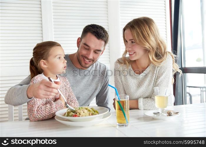 family, parenthood, food and people concept - happy mother, father and little girl eating pasta for dinner at restaurant or cafe