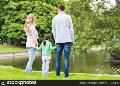 family, parenthood, leisure and people concept - mother, father and little girl walking in summer park near pond