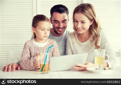 family, parenthood, technology and people concept - happy mother, father and little girl with tablet pc computer having dinner at restaurant. happy family with tablet pc at restaurant