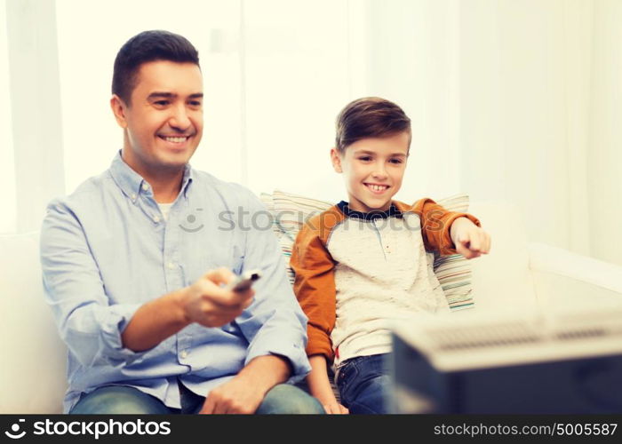 family, people, technology, television and entertainment concept - happy father and son with remote control watching tv at home. smiling father and son watching tv at home