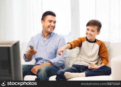 family, people, technology, television and entertainment concept - happy father and son with remote control watching tv at home