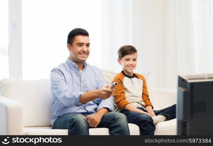 family, people, technology, television and entertainment concept - happy father and son with remote control watching tv at home