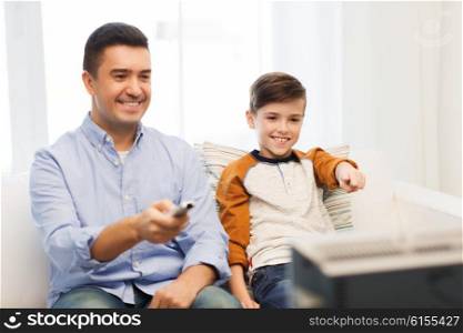 family, people, technology, television and entertainment concept - happy father and son with remote control watching tv at home
