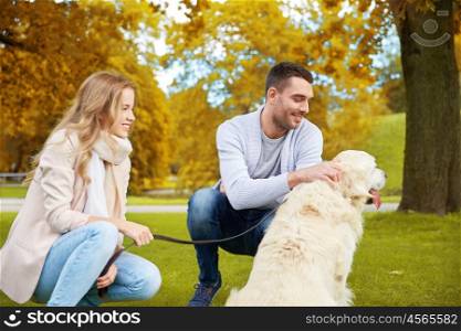 family, pet, animal and people concept - happy couple with labrador retriever dog walking in autumn city park