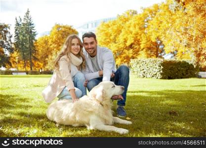family, pet, animal and people concept - happy couple with labrador retriever dog walking in autumn city park