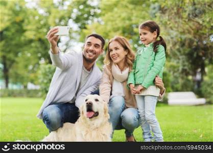 family, pet, animal, technology and people concept - happy family with labrador retriever dog taking selfie by smartphone in park