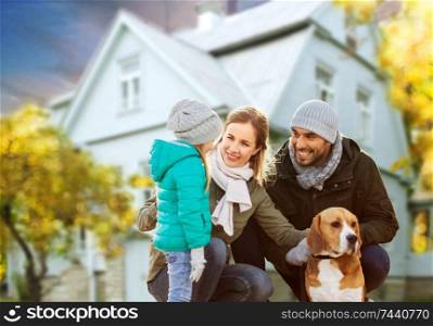 family, pets and people concept - happy mother, father and little daughter with beagle dog outdoors over house in autumn background. happy family with dog over house in autumn