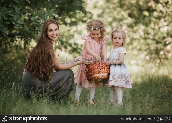 family photo mom with daughters in the park. Photo of young mother with two cute kids outdoors in spring time, beautiful woman with daughter having fun. Mother&rsquo;s day concept. family photo mom with daughters in the park. Photo of young mother with two cute kids outdoors in spring time, beautiful woman with daughter having fun
