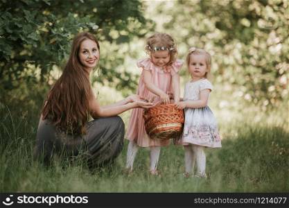 family photo mom with daughters in the park. Photo of young mother with two cute kids outdoors in spring time, beautiful woman with daughter having fun. Mother&rsquo;s day concept. family photo mom with daughters in the park. Photo of young mother with two cute kids outdoors in spring time, beautiful woman with daughter having fun