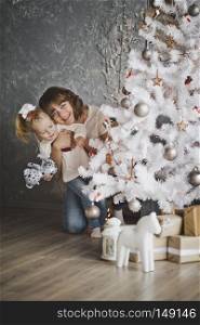 Family photos among the Christmas decorations.. Mother and daughter are happily playing around the Christmas tree 7124.
