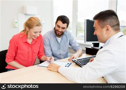 family planning, medicine, fertility and healthcare concept - happy couple visiting doctor and filling form at clinic. couple visiting doctor at family planning clinic