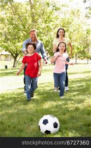 Family playing football in park