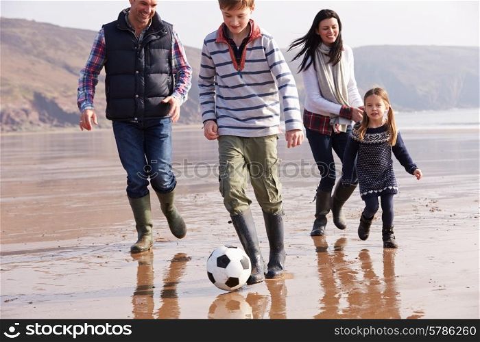 Family Playing Football On Winter Beach