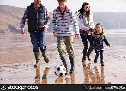 Family Playing Football On Winter Beach