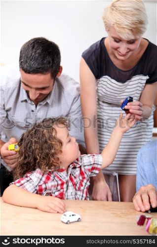 Family playing with a boy&rsquo;s toy cars