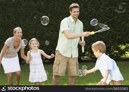 Family Playing With Bubbles In Garden